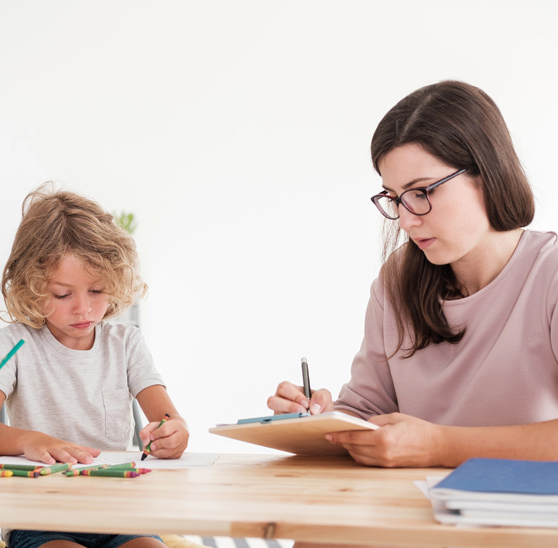 Boy drawing picture while psychologist taking notes during therapy