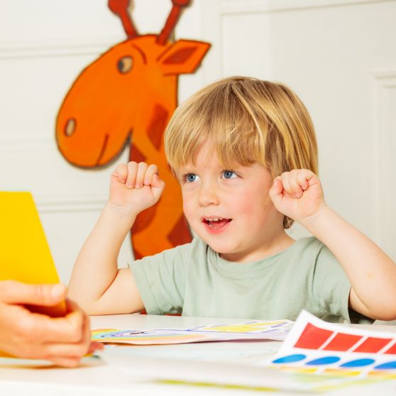 Early development lesson - little blond boy engaged in the process lift hands looking at the picture in the book